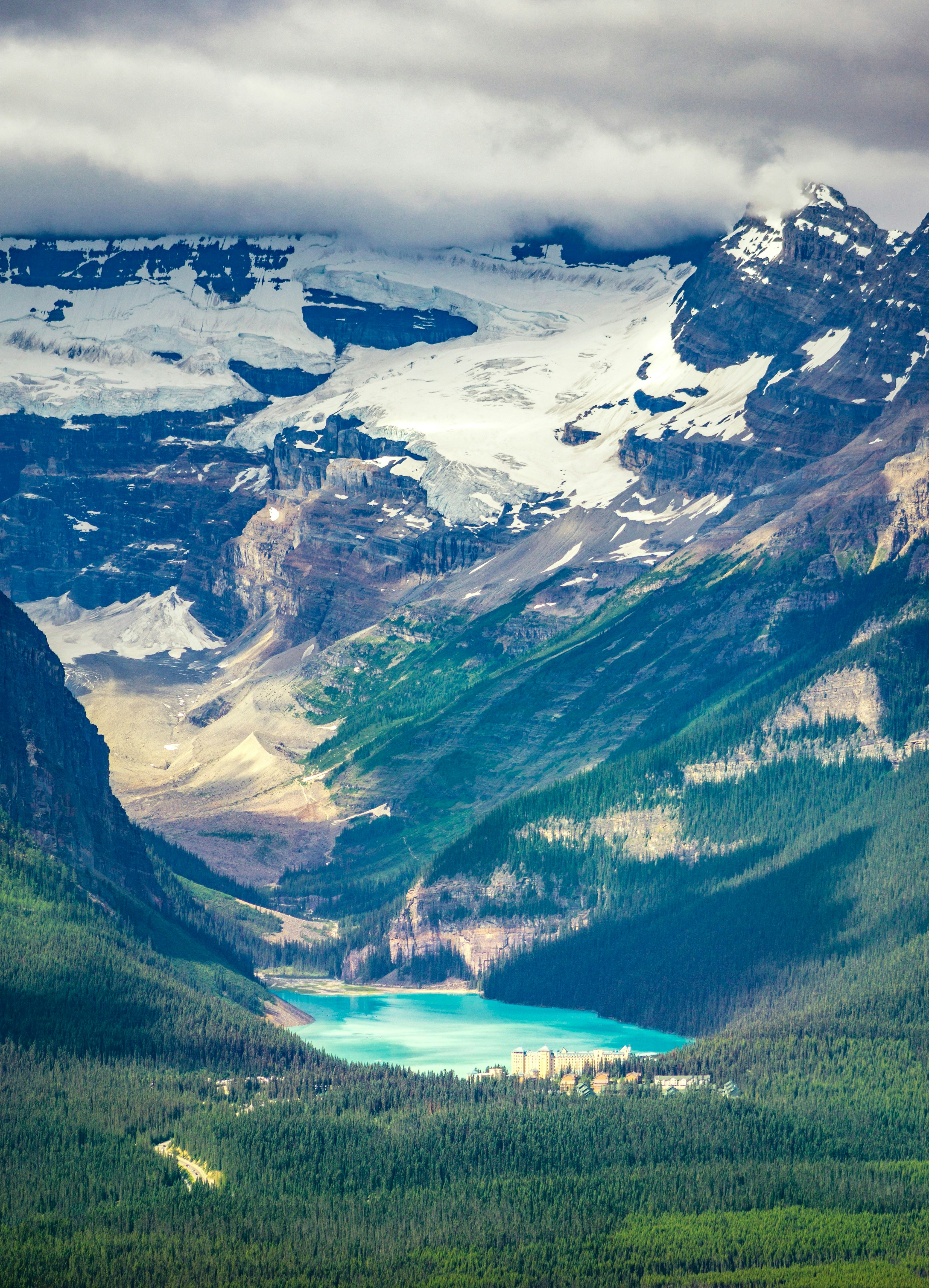 green and white mountains near lake under white clouds and blue sky during daytime